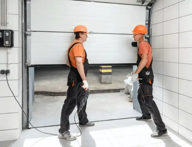 Two workers installing a garage door.